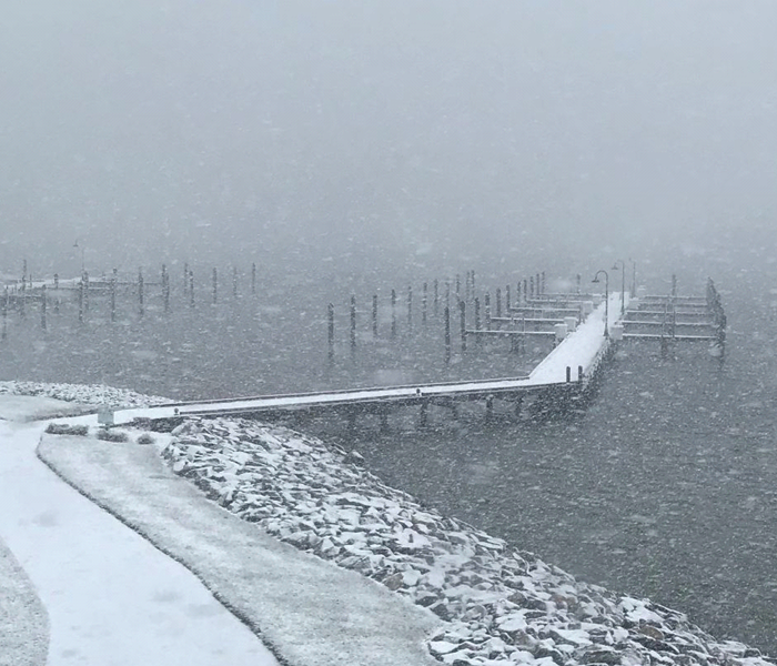 A pier covered in snow is shown as it extends into the water.